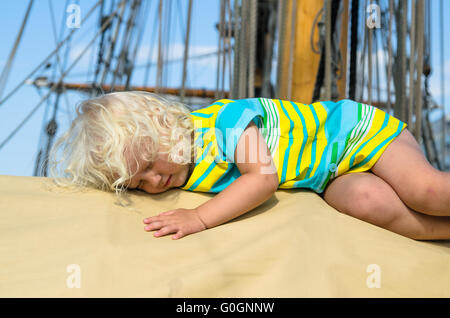 Das kleine Mädchen schlief auf dem Deck eines Segelbootes Stockfoto