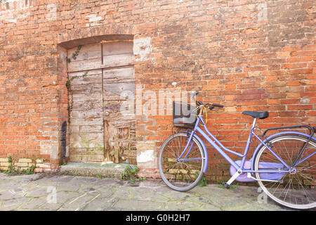 altes violettes Fahrrad geparkt lange eine Außenwand in Insel Burano, Venedig Stockfoto