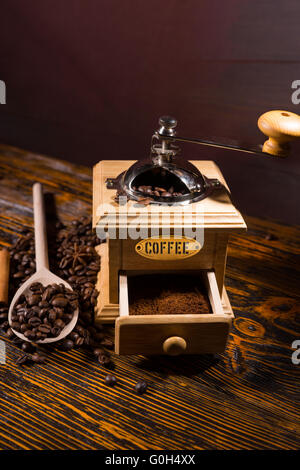High Angle View of frisch gemahlener Kaffee im traditionellen Handschleifmaschine auf rustikalen Holztisch mit gerösteten Kaffeebohnen und Textfreiraum. Stockfoto
