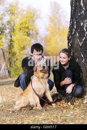 Glückliches junges Paar mit Hund im Herbst Park spielen Stockfoto