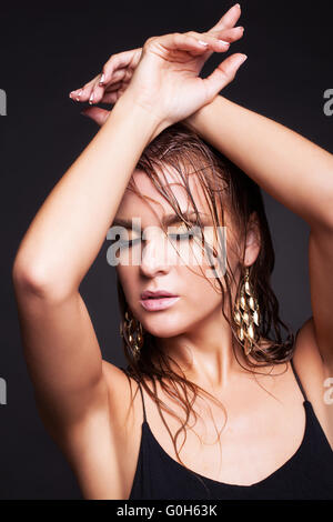 Frau mit nassen glänzenden Make-up und geschlossenen Augen auf schwarzem Hintergrund Stockfoto