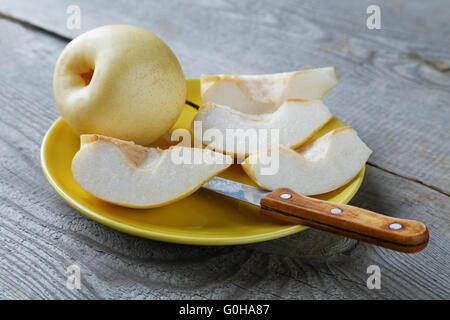 geschnittene gelbe Birne in einer Schüssel auf einem rustikalen Tisch Stockfoto