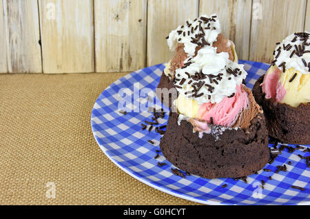Neapolitanische Eisbecher mit Schlagsahne und Schokolade Streusel in Brownie Bogen. Stockfoto