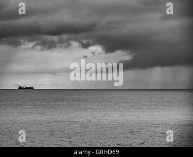 Container schiff am Horizont in Richtung Sturm Stockfoto