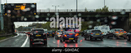 Stau auf der Autobahn, Regen auf windsreen, rote Bremsleuchten, Overhead Schild Warteschlange Vorsicht Stockfoto