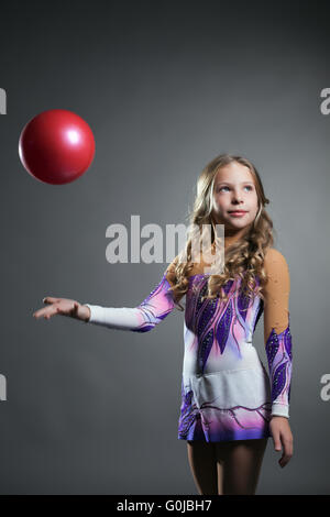 Schöne künstlerische Turnerin wirft Ball im studio Stockfoto