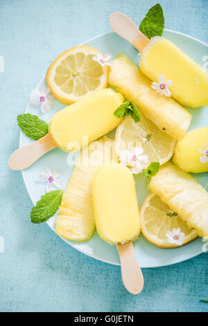 Zitrone und Ananas Eis am Stiel mit frischen Früchten und essbaren Blüten Stockfoto