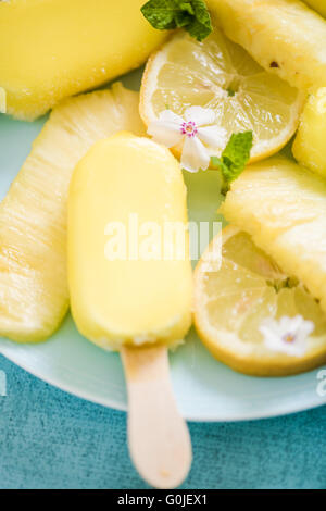 Zitrone und Ananas Eis am Stiel mit frischen Früchten und essbaren Blüten Stockfoto