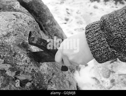 Hand des tapferen Ritters versucht, das magische Schwert Excalibur in den Stein zu entfernen Stockfoto