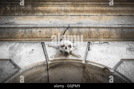 Ein Stein Schädel platziert neben dem Eingang ein Beinhaus in einem italienischen Friedhof. Stockfoto