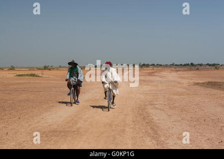 Zwei afrikanische Männer auf Fahrrädern in der Sahel-Landschaft in Mali, Westafrika Stockfoto