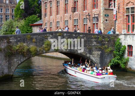 Boot voller Touristen fahren Sie unter der Brücke in Blinde-Ezel Huidenvettersplein, Brügge, Belgien. Stockfoto