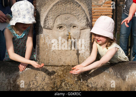 Tourist Touristen Kind Kinder Kind Kinder trinken / trinken aus einem öffentlichen Wasserhahn Brunnen in römischen Pompeji Pompei. Neapel Italien Stockfoto