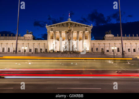 Die Außenseite des österreichischen Parlamentsgebäude in Viennat in der Nacht. Die Unschärfe einer Straßenbahn kann gesehen werden, im Vordergrund vorbei Stockfoto