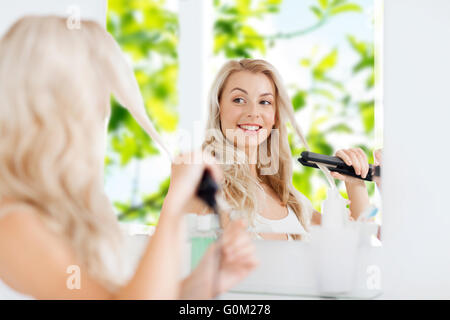 Frau mit Glätteisen dabei ihre Haare im Bad Stockfoto