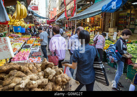 Menschen zwischen den Ständen voller Früchte und Gemüse auf dem Straßenmarkt in Tai Po, Hong Kong, China. Stockfoto