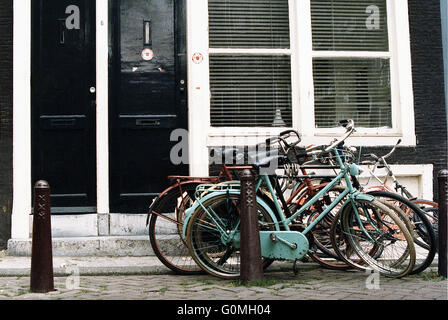 Eine aufrechte Haufen von Fahrrädern propped up an einem bordstein Poller. Stockfoto