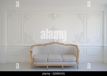 Wohnzimmer mit antiken stilvolle Licht Sofa auf Luxus weiße Wand Basrelief Stuck Zierleisten-Jahrgang Designelemente Stockfoto