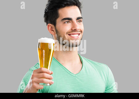 Porträt von gut aussehenden jungen Mann Verkostung ein Bier vom Fass, auf grauem Hintergrund isoliert Stockfoto