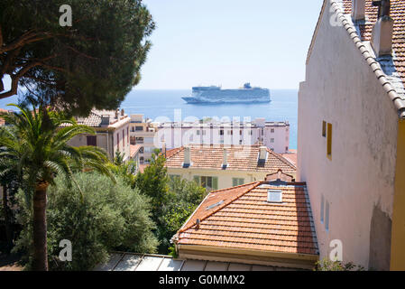 Ein Kreuzfahrtschiff in Cannes, Frankreich, gesehen durch Gebäude in der Altstadt Le Suquet festgemacht. Stockfoto