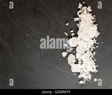 Draufsicht der Magnesium-Chlorid Flocken auf einem dunklen Granit Schiefer. Stockfoto
