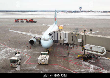 Air Canada Jet am Gate mit Schneeräumausrüstung auf der Landebahn, Ottawa Macdonald-Cartier International Airport. Stockfoto