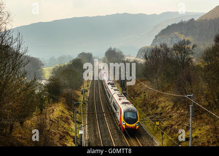 Jungfrau Pendolino trainieren auf der West Coast Main Line neben der Autobahn M6 in Lune Schlucht in der Nähe von Tebay, Cumbria Stockfoto