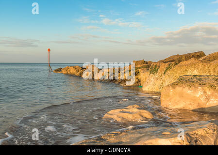 Am frühen Morgen am felsigen Strand von Westbay in England, Bojen mit beruhigende Aufnahmen von der Gefahr-Marker in der frühen Morgensonne Stockfoto
