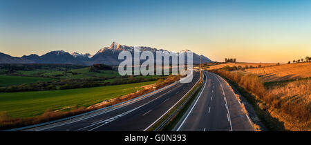 Panorama view of the High Tatra mountains with mount Krivan and a local highway in Slovakia at sunset Stockfoto