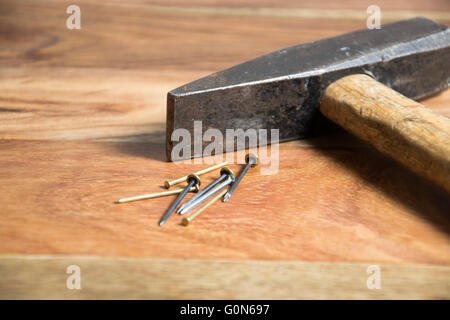 Hammer mit Nägeln auf hölzernen Hintergrund Stockfoto