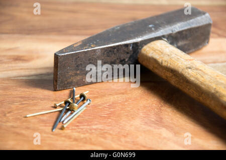 Hammer mit Nägeln auf hölzernen Hintergrund Stockfoto