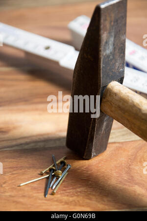 Hammer mit Nägeln auf hölzernen Hintergrund Stockfoto