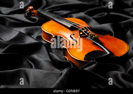 Alte Geige auf dunklen Stoff Textur Stockfoto