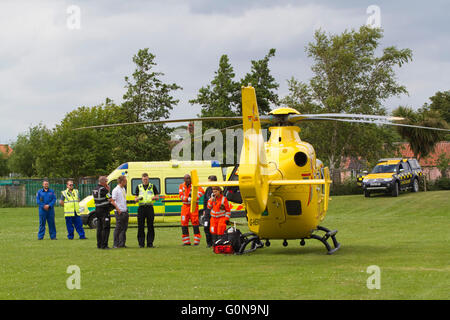 East Anglia Air Ambulance in ein Feld mit einem Straßenfahrzeug Krankenwagen und Coast Guard mit vielen Einsatzkräfte Stockfoto