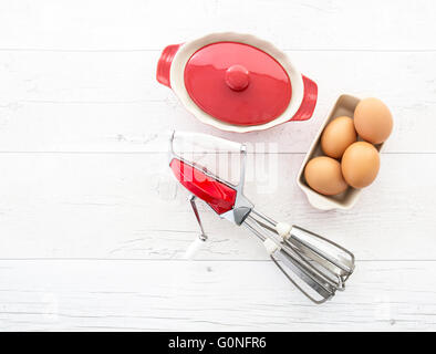 Vintage Rot Metall Hand Schuss auf Retro-weißen hölzernen Hintergrund und Schüssel Eier verquirlen Stockfoto