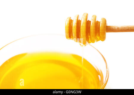 Dipper für Honig und Honig in einer Schüssel auf einem weißen Hintergrund Stockfoto