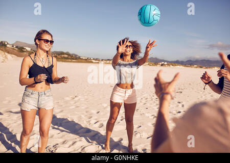 Porträt der jungen Frau spielen Volleyball mit Freunden am Strand. Gruppe von Freunden Volleyball spielen. Stockfoto