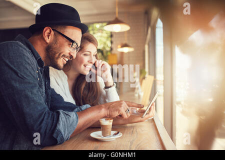 Lächelnd junges Paar in einem Coffee-Shop mit Touchscreen-Computer. Junger Mann und Frau in einem Restaurant mit Blick auf digital-Tablette Stockfoto