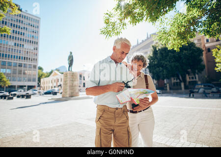 Älteres Paar mit einem Stadtplan für Lage in der Stadt. Reifer Mann und Frau zusammen im Freien im Stadt mit einer Karte. Stockfoto