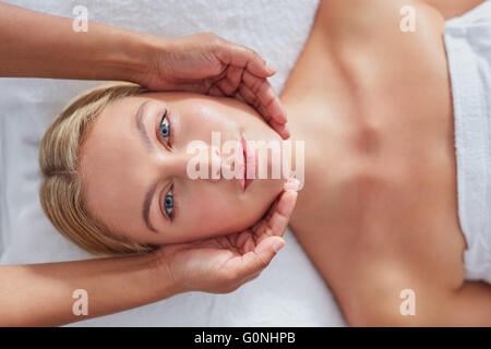 Schuss von schöne junge Frau, ein Gesicht im Health Spa massage hautnah. Kaukasische Gesicht und Masseurin Hände. Stockfoto