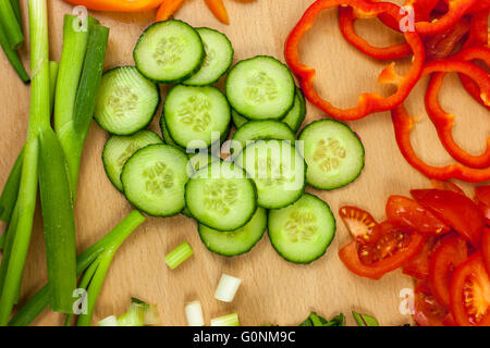 Frisch geschnittene englische Gurke von oben geschossen umgeben von anderen gehackten Gemüse Stockfoto