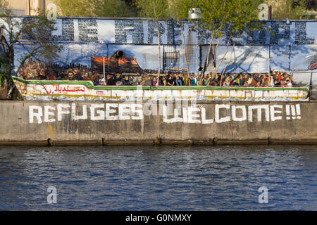 Berlin, Deutsch - 30. April 2016: Flüchtlinge aufzunehmen, Graffiti und Flüchtling Boot Malerei in Berlin, Deutschland. Stockfoto