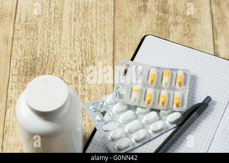 Tabletten auf hölzernen Schreibtisch mit Notizblock und Stift Stockfoto