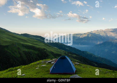 Ein einsames Zelt am Hang in einer weiten Berglandschaft Stockfoto