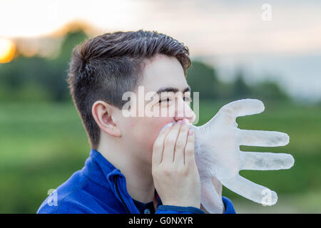 Nahaufnahme eines jungen in Landschaft während bläst in eine Einweg-Kunststoff-Handschuh lächelnd, es aufzublasen Stockfoto