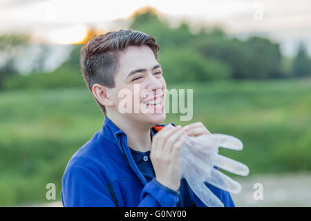 Nahaufnahme eines jungen mit Hosenträgern in Natur lachen beim Schlag in eine Einweg-Kunststoff-Handschuh gonna es aufzublasen Stockfoto