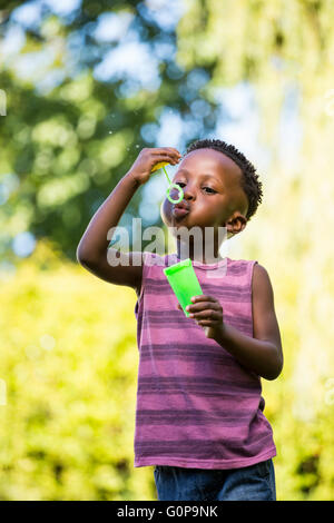 Niedliche Mischenrennen junge spielt mit Seifenblasen Stockfoto