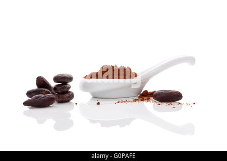 Kakaobohnen und Kakaopulver in einer Schüssel weiß und weiße Löffel auf weißem Hintergrund. Gesunde Superfood. Stockfoto