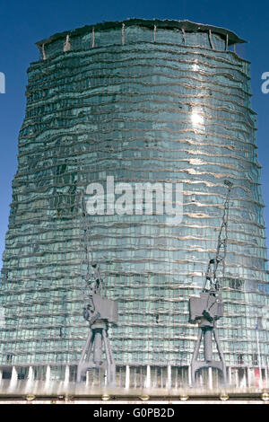 Spiegelungen im Wasser am West India Docks am Canary Wharf London Docklands dock Krane vor Hochhaus Bild invertiert Stockfoto