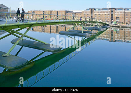 Fußgängerbrücke, Gartenrestaurants & umgebauten Lagerhäusern spiegelt sich in North Dock der West India Docks am Canary Wharf Isle Of Hunde London England UK Stockfoto